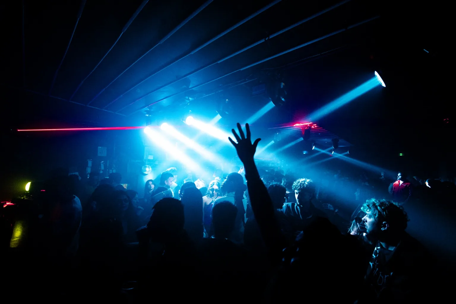 Crowd with raised hands beneath blue lasers at Project Kulture.