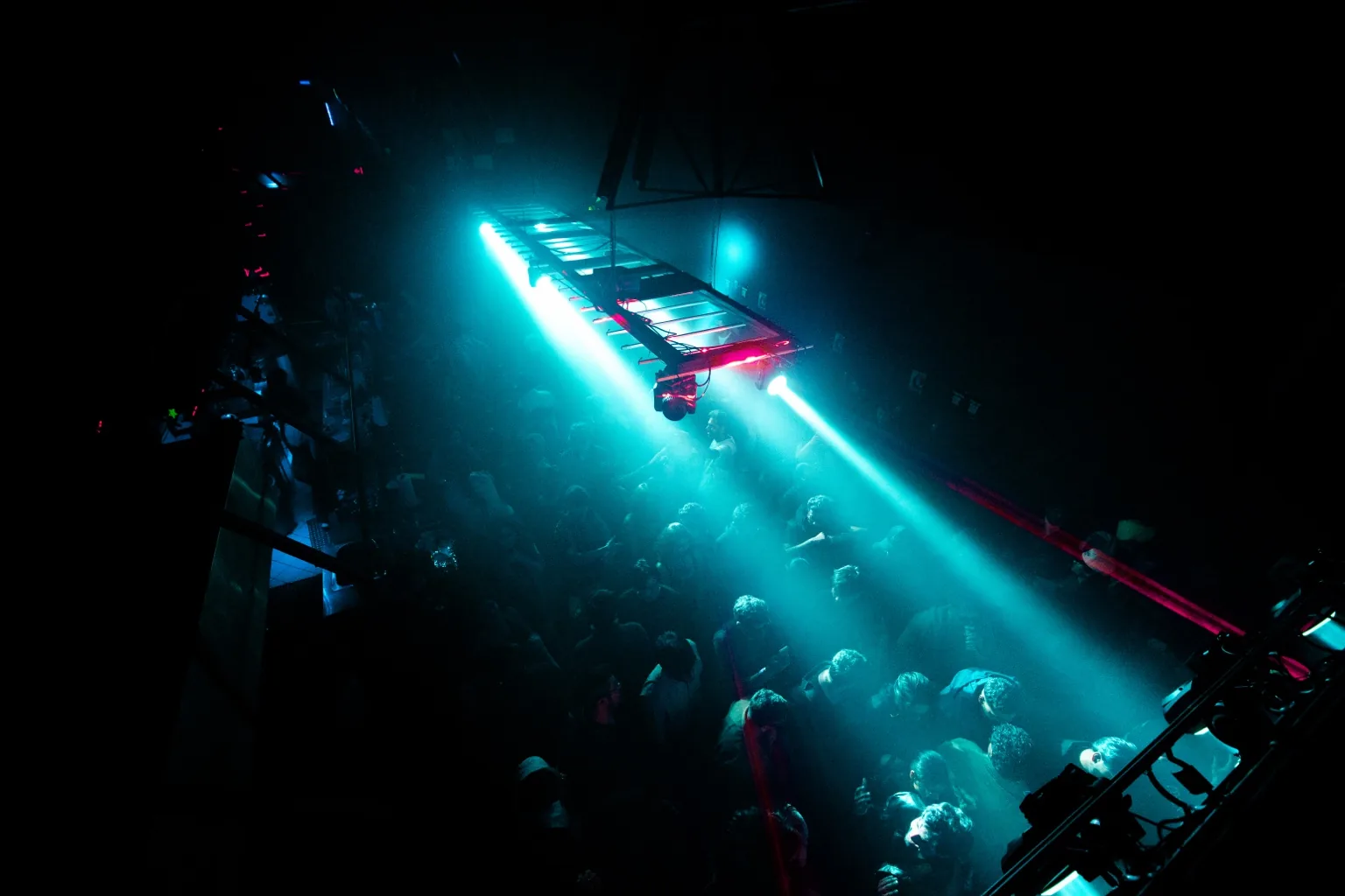 Crowd beneath intersecting green and blue lights at Project Kulture.