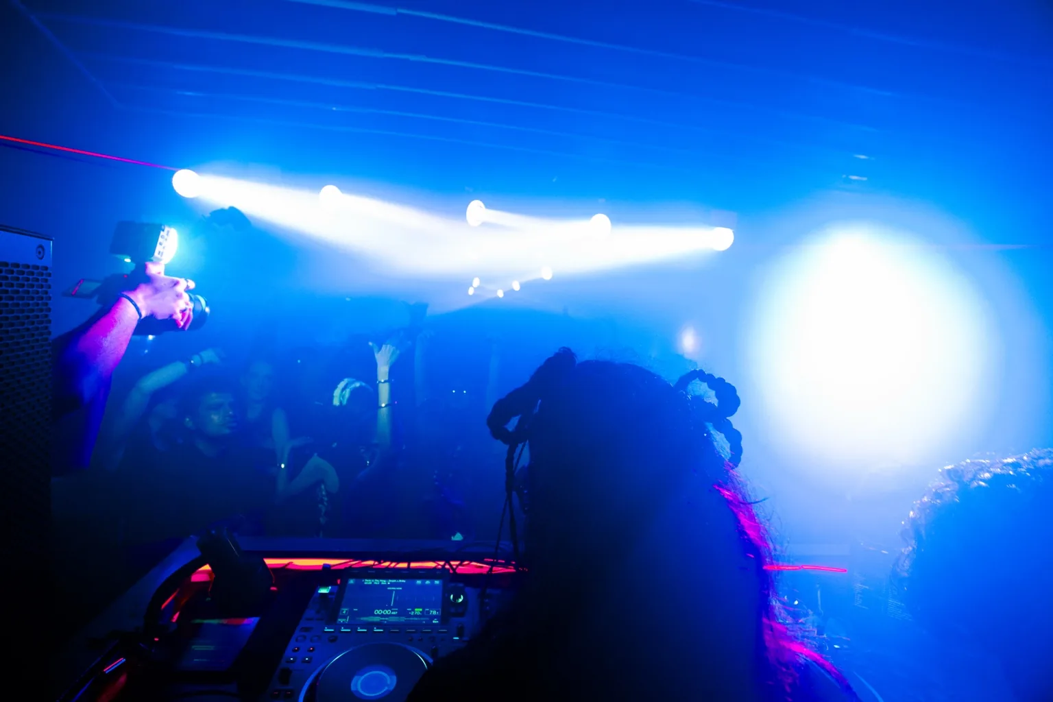 DJ booth facing a crowd under blue and white lights at Project Kulture.