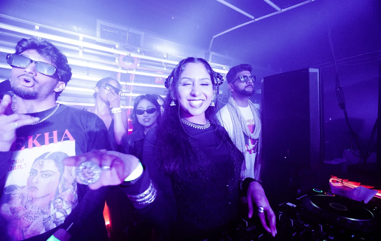 Guests beside the DJ booth under purple lights at Project Kulture.