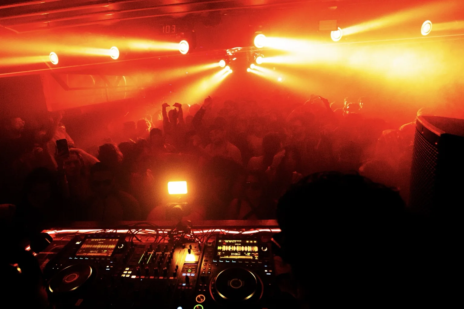 DJ equipment overlooking a crowd beneath orange lights at Project Kulture.