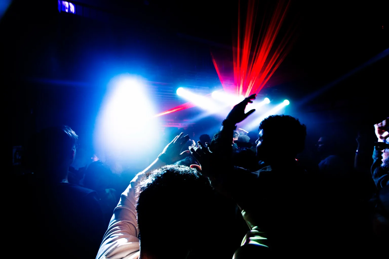 Crowd silhouettes beneath blue and red beams at Project Kulture.