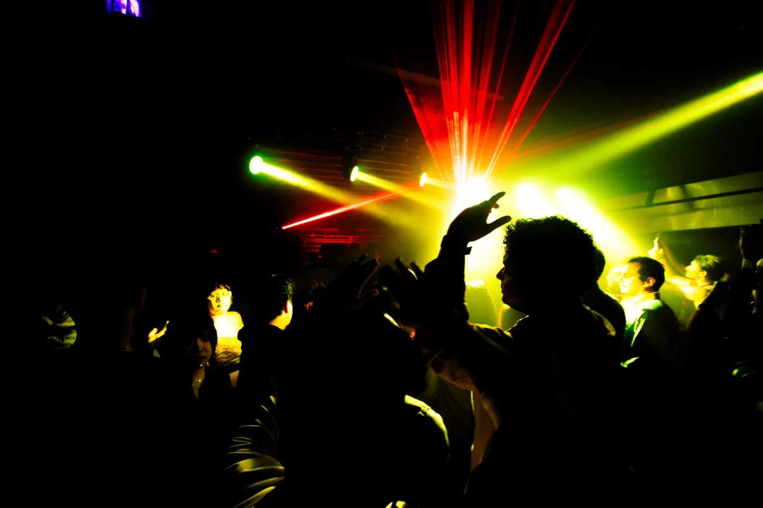 Raised hands silhouetted against yellow stage lights at Project Kulture.