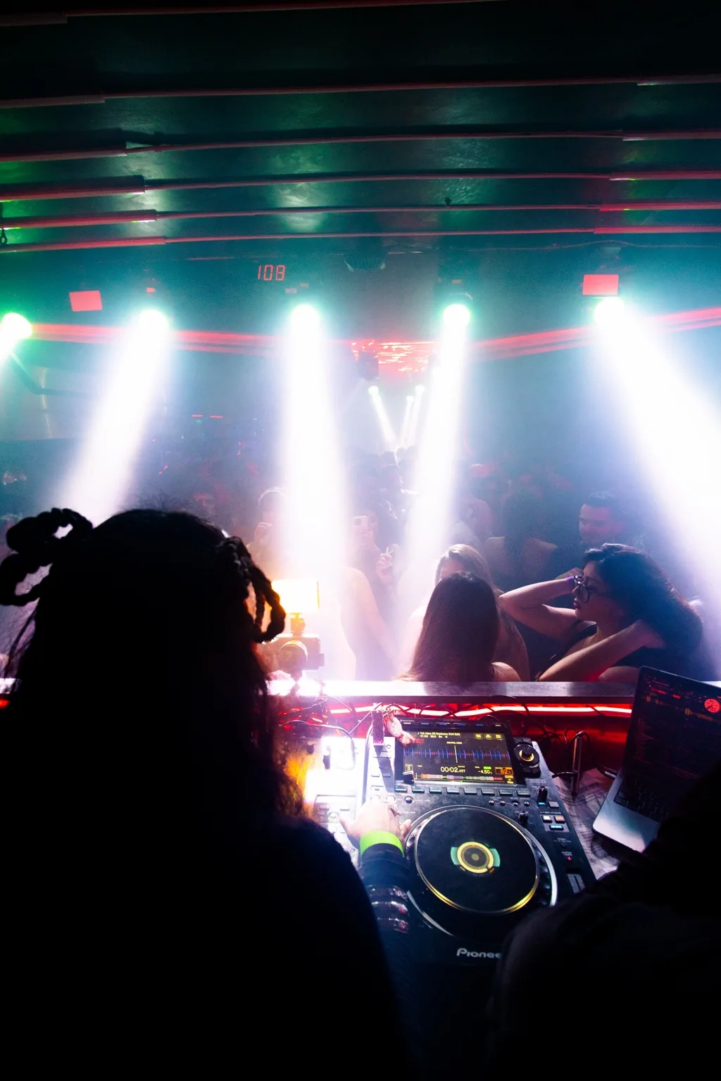 DJ and dance floor beneath white and red beams at Project Kulture.