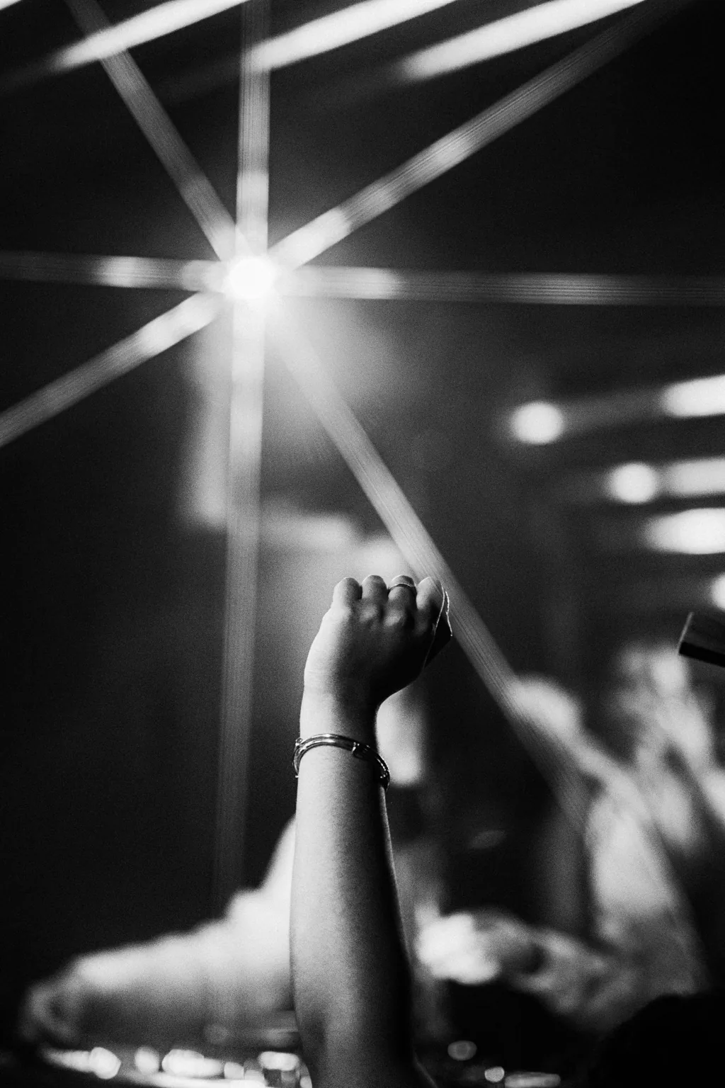Black and white raised hand beneath venue lights at Project Kulture.
