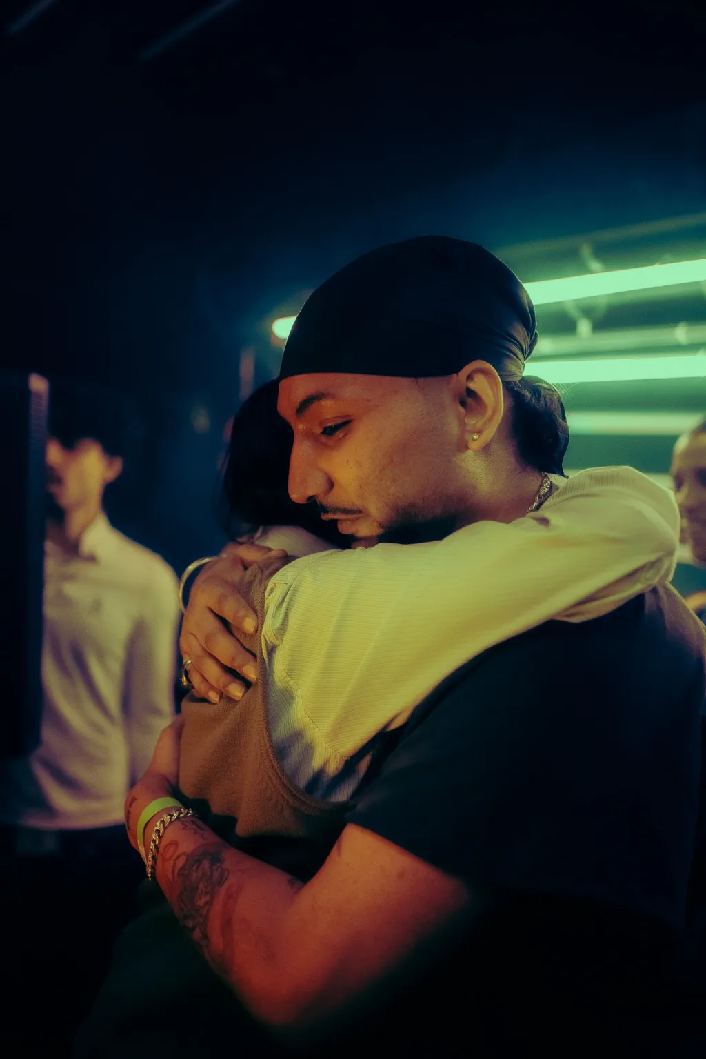 Two guests embracing beneath green lights at Project Kulture.