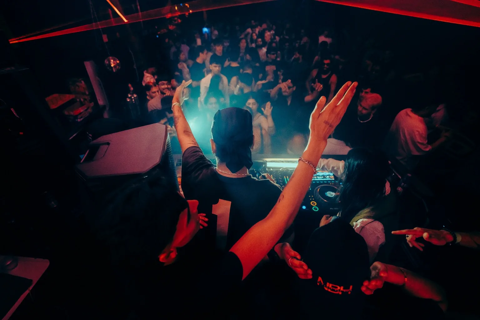 View over the DJ booth toward a cheering crowd at Project Kulture.
