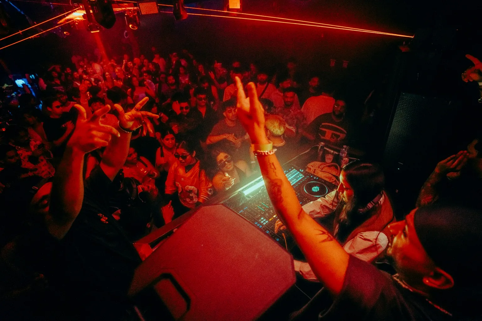 DJ raising an arm toward a packed dance floor at Project Kulture.