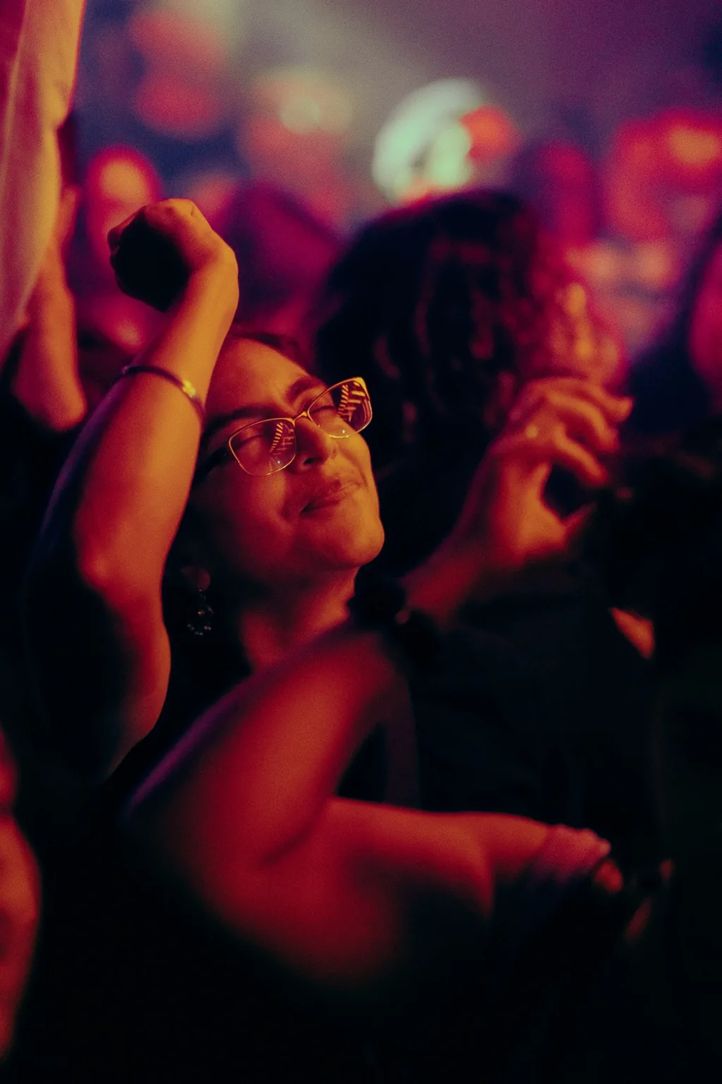 Guest dancing with an arm raised under red lights at Project Kulture.