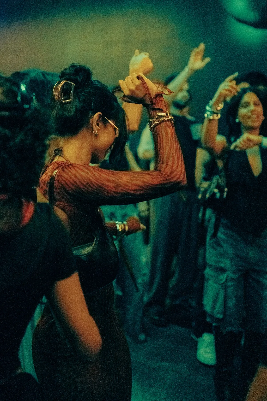 Guest dancing with an arm raised beneath green lights at Project Kulture.