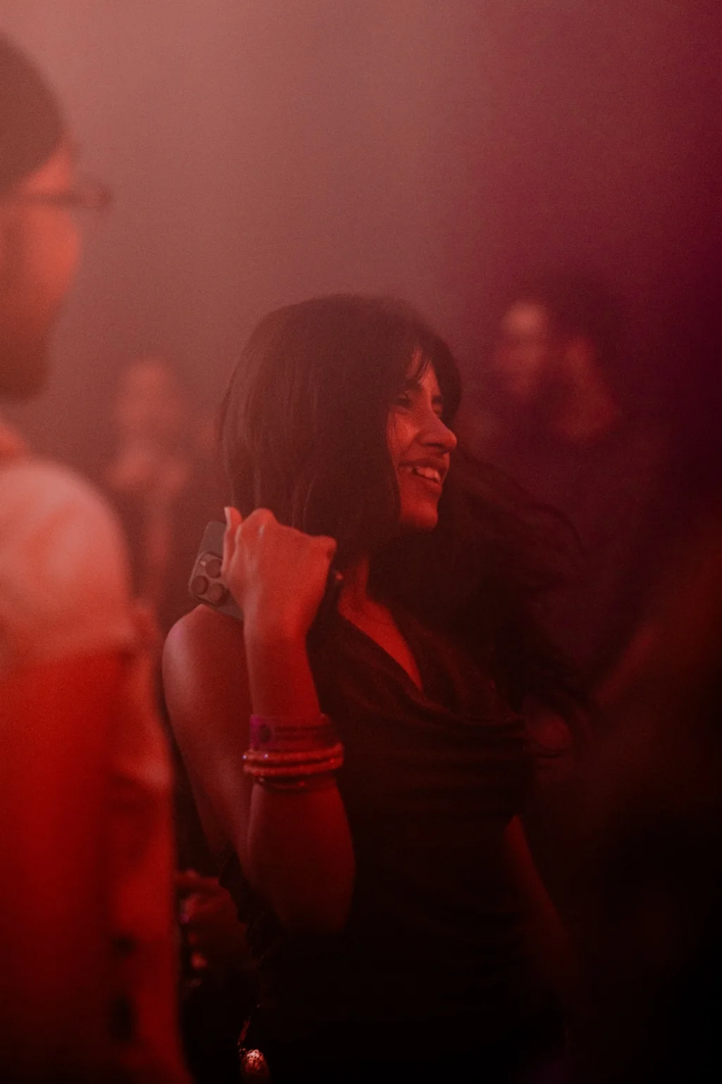 Guest smiling in red lit haze at Project Kulture.