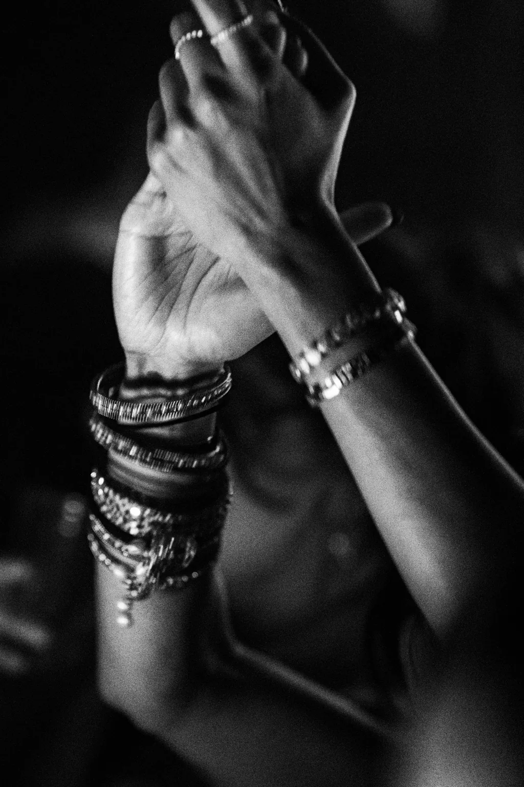 Black and white close up of raised hands and bracelets at Project Kulture.
