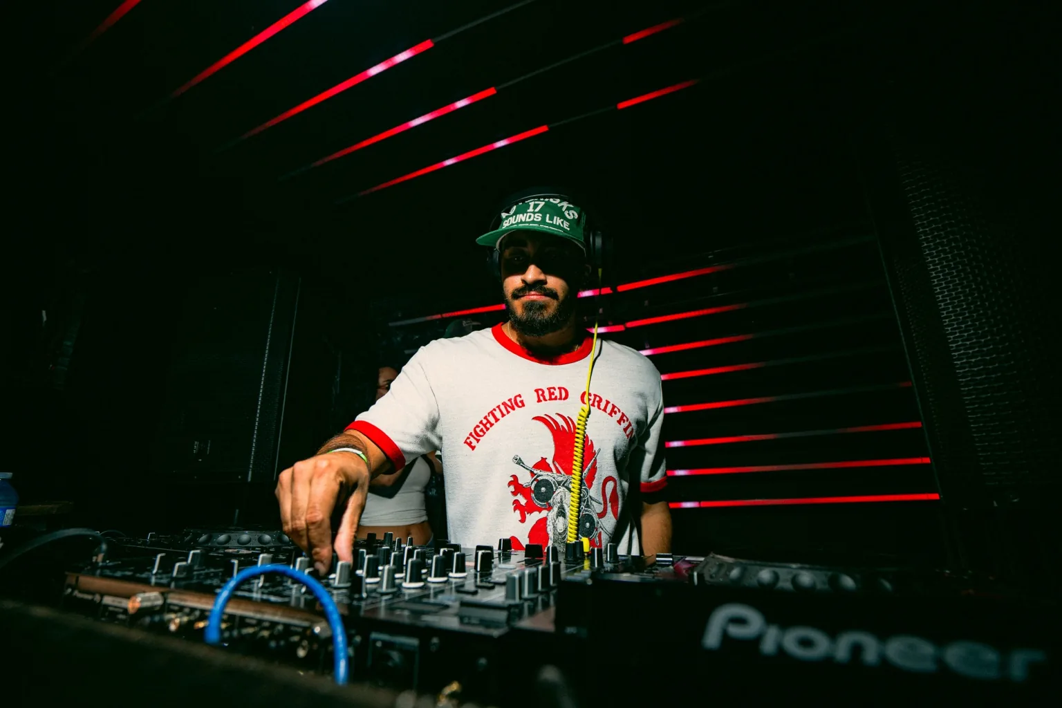 DJ working the mixer beneath red light bars at Project Kulture.