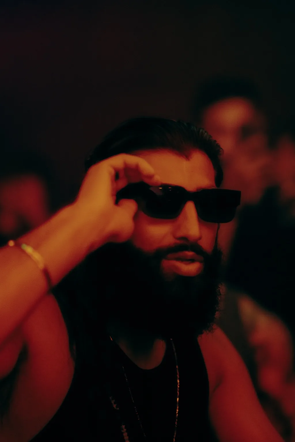 Guest adjusting sunglasses under red lighting at Project Kulture.