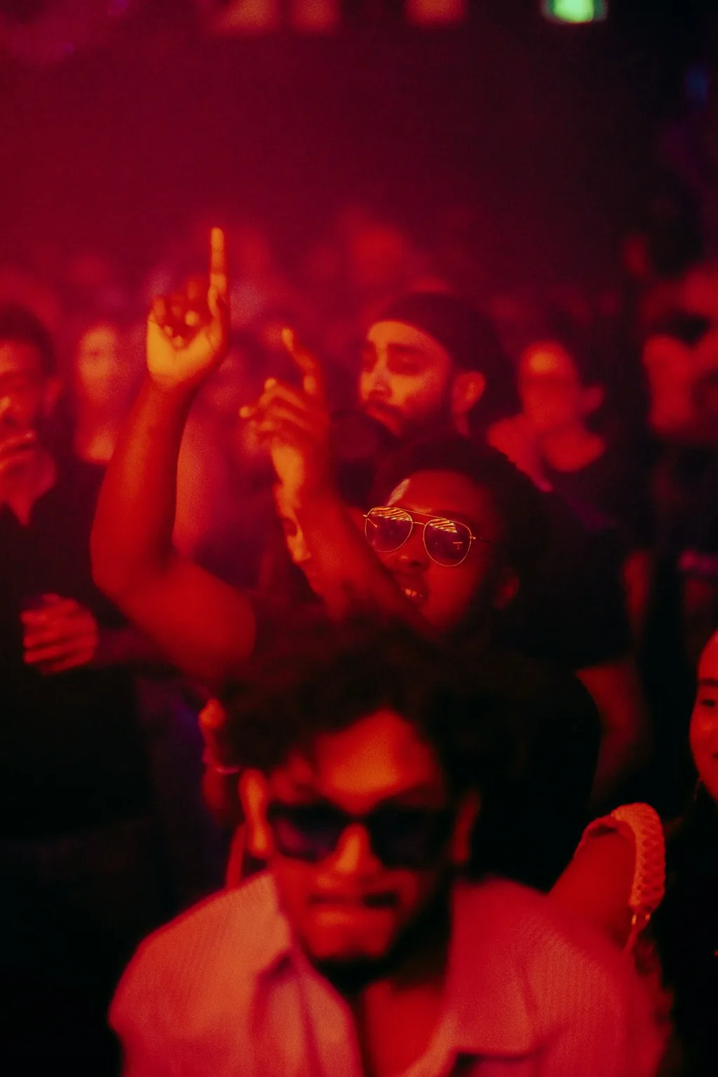 Crowd under red lights with a guest wearing sunglasses at Project Kulture.